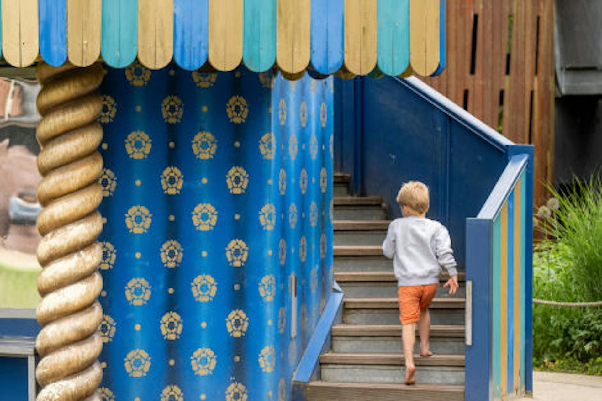 Blue and gold playground metalwork with stairs, handrails and decorative panels at the Magic Garden